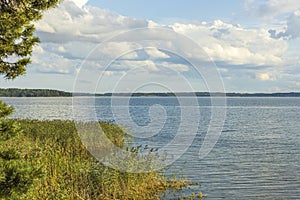 Gorgeous summer landscape view.  Baltic sea water mirror surface and blue sky with white clouds background.