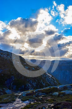 Gorgeous sunbeams pass through the clouds illuminating the mountain range where the path to Kjeragbolten lies. Norway