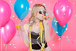 Gorgeous trendy young woman in party outfit celebrating birthday. Party mood, balloons, flying confetti, cocktail and dancing.