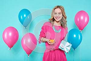 Gorgeous trendy young woman in party outfit holding cocktail and a gift box. Birthday Party concept.