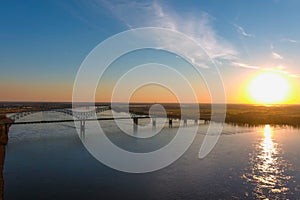 The gorgeous vast flowing water of the Mississippi river with a stunning blue, yellow and red sunset in the sky with a bridge over