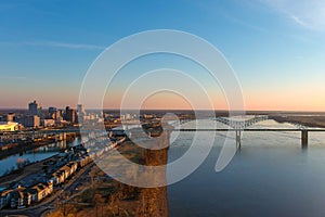 The gorgeous vast flowing water of the Mississippi river with a stunning blue, yellow and red sunset in the sky with a bridge over