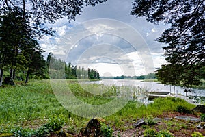 Gorgeous view of forest lake landscape on blue sky and white clouds background. Sweden.