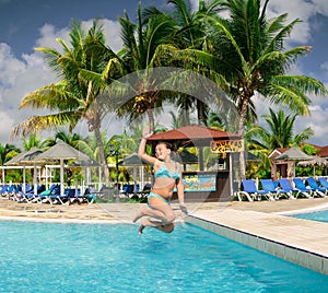 Gorgeous view of happy joyful little girl jumping in tropical swimming pool