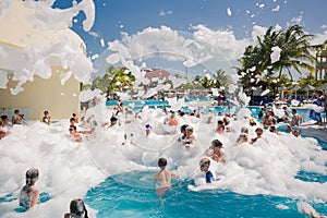 Gorgeous view of happy smiling joyful people relaxing and enjoying their time in swimming pool foam party on sunny day