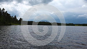 Gorgeous view of nature landscape. High trees on lake coast. Thunder sky with gray clouds background. Cloudy summer d