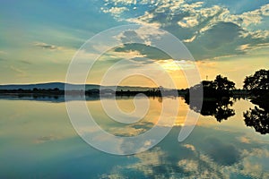 Gorgeous view of a reflective lake with a golden sun above it in Burla, Odisha India at sunset photo