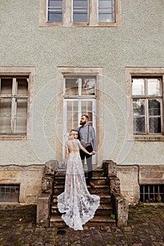 Gorgeous wedding couple hugging and walking near old castle in sunny beautiful park. Stylish beautiful bride and groom posing on