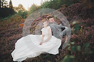 Gorgeous wedding couple kissing and hugging in forest with big rocks