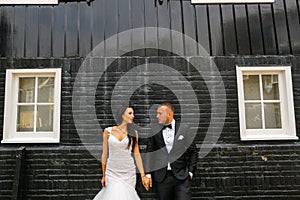 Gorgeous wedding couple posing in front of black black brick wall