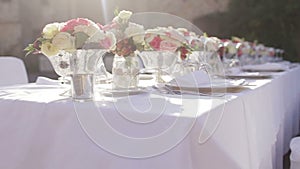 Gorgeous wedding table setting for fine dining outdoors decorated with flowers