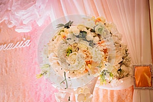 Gorgeous white bouquet stands before light pink curtain