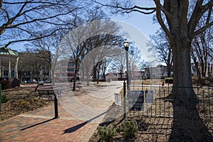 A gorgeous winter landscape at the Marietta Square with red brick footpath, a water fountain, bare trees, pink trees