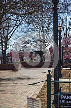 A gorgeous winter landscape at the Marietta Square with red brick footpath, a water fountain, bare trees, pink trees