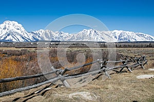 Gorgeous winter landscape of the Teton mountains in the background and a split rail fence in the foreground.