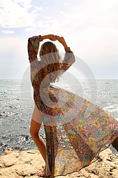 Gorgeous woman with blond hair in elegant swimsuit posing on beach