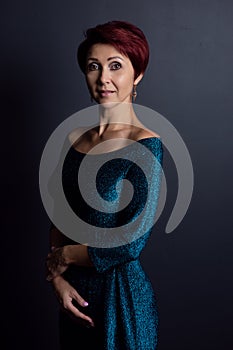 Gorgeous woman in elegant evening dress posing on a dark background