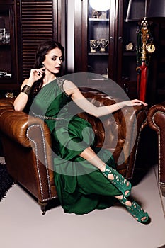 Gorgeous woman in elegant green dress posing in luxurious interior