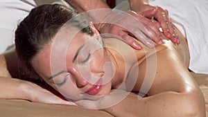 Gorgeous woman enjoying back massage at spa, smiling to the camera