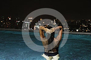 Gorgeous woman in infinity swimming pool on the roof on tall building