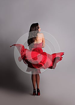 gorgeous woman in red dress. Studio picture, grey background