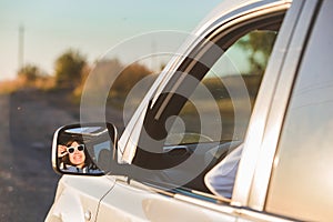 gorgeous woman in sunglasses reflection in car mirror on sunset