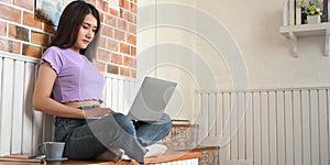 Gorgeous woman using computer laptop that putting on her lap while sitting.