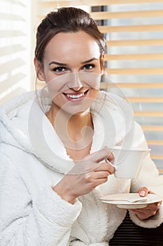 Gorgeous woman in white bathrobe with toothy smile