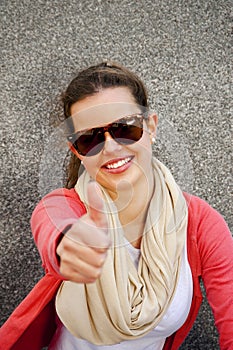 Gorgeous young brunette showing big thumbs up on urban location.