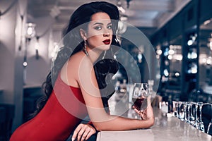 Gorgeous young brunette woman in red dress with wine