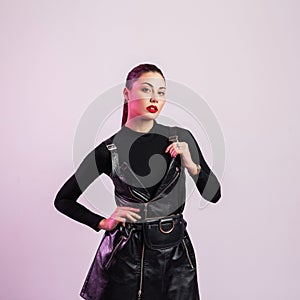 Gorgeous young brunette woman with trendy hairstyle in vintage shirt in leather fashionable black sexy dress posing in the studio