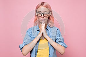 Gorgeous young caucasianwoman in glasses, holding hands in namaste or prayer