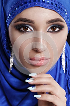 Gorgeous Young East Woman face portrait in hijab. Beauty Model Girl with bright eyebrows, perfect make-up, touching her