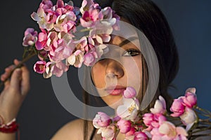 Gorgeous young girl with colorful flowers, studio portrait