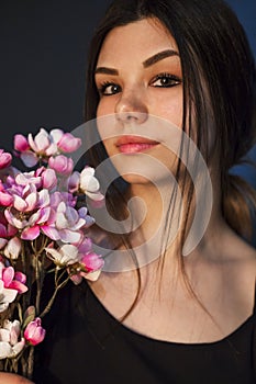 Gorgeous young girl with colorful flowers, studio portrait