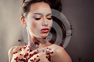 Gorgeous young girl with pink make-up with pomegranate seeds