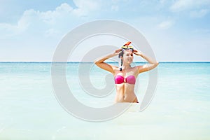 Gorgeous, young lady in pink swimwear with a snorkeling mask swimming in the sea