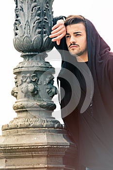 Gorgeous young man leaning against a old lamppost