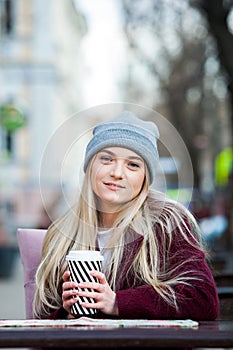 Gorgeous young woman with cup of coffee in city street. Coffee break. Coffee to go. Stylish hipster girl drinking coffee in street
