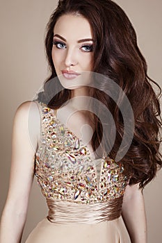 Gorgeous young woman with dark hair and evening makeup, wears luxurious dress