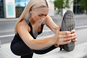 Gorgeous young Woman Doing Stretching Exercise At Sidewalk In City photo