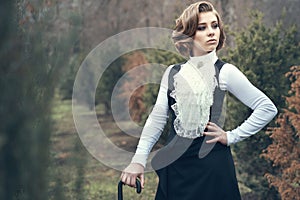 Gorgeous young woman with elegant Victorian hairstyle walking in the misty autumn park