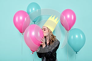 Gorgeous young woman in leather jacket and party hat kissing colourful balloon. Birthday party concept.