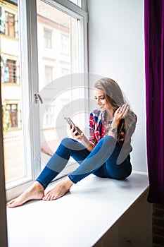 Gorgeous young woman with long red hair checking email and sending sms message on mobile phone