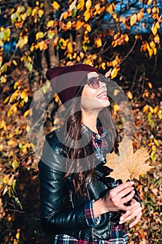 Gorgeous young woman posing in sunglasses in sunny autumn day in park