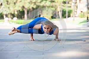 Gorgeous young woman practicing yoga outdoor. Calmness and relax, female happiness concept Blurred background