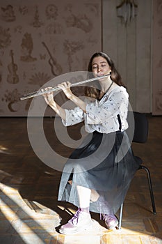 A gorgeous young woman sitting and playing the flute