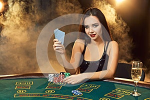 Gorgeous young woman sitting at poker table with glass of champagne
