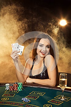 Gorgeous young woman sitting at poker table with glass of champagne