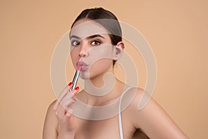 Gorgeous young woman in stylish makeup. Girl posing with new lipstick in studio. Sexy girl rouging her lips. Sexy model